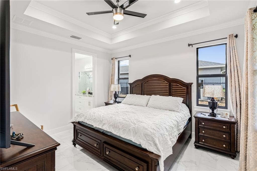 Bedroom featuring baseboards, visible vents, a raised ceiling, and crown molding