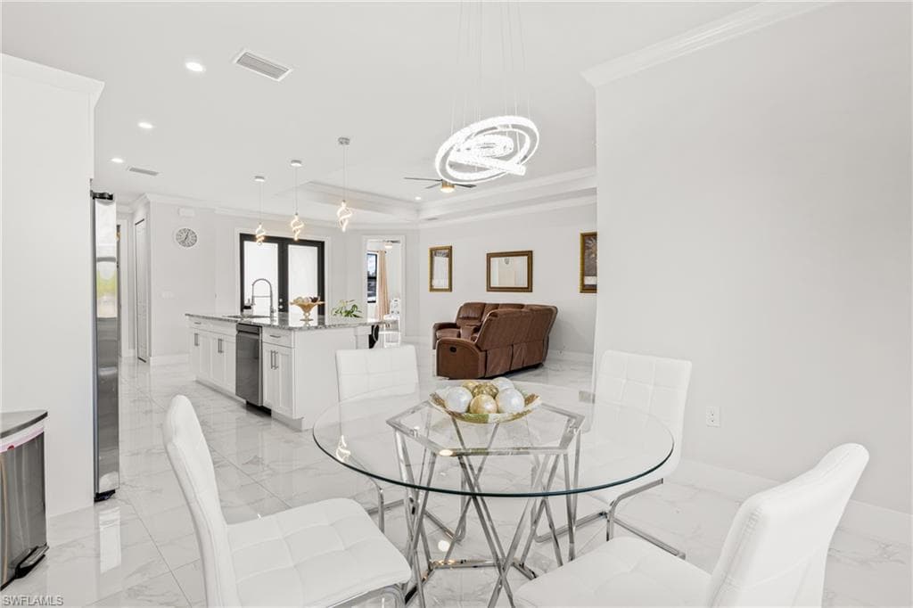 Dining room with visible vents, ornamental molding, marble finish floor, a tray ceiling, and recessed lighting