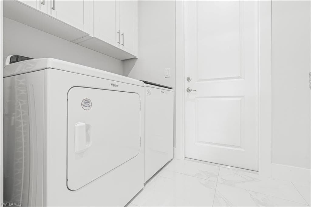 Laundry area featuring marble finish floor, cabinet space, and washing machine and clothes dryer