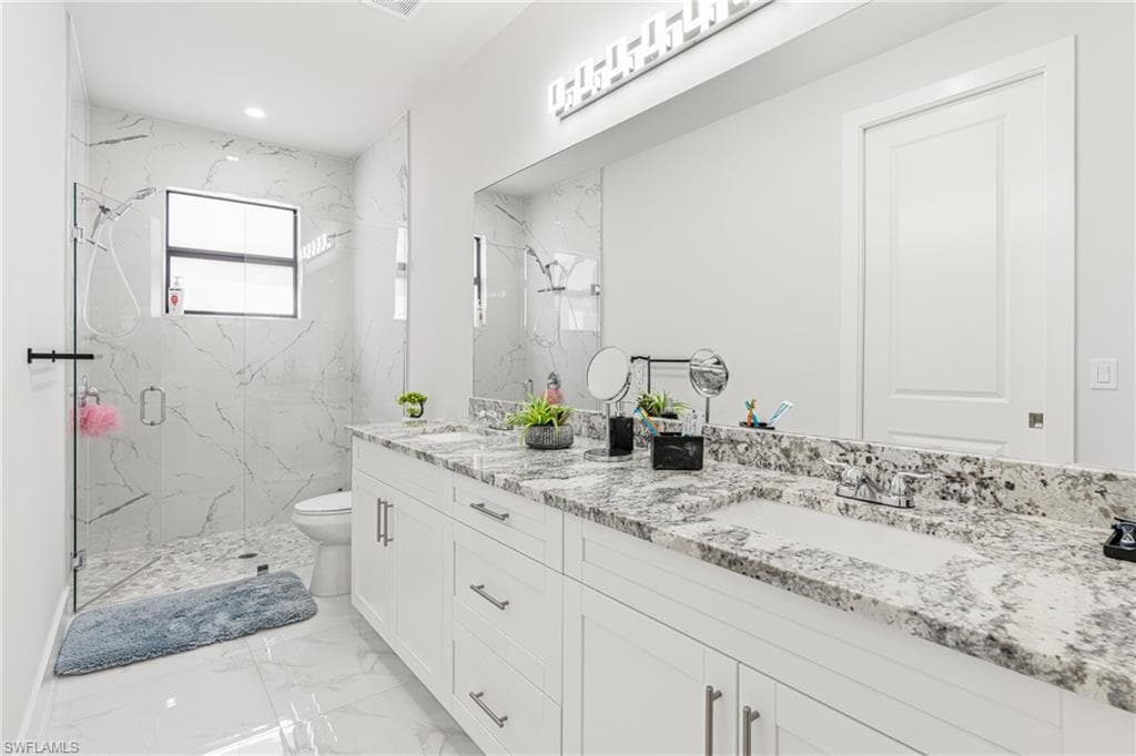 Bathroom featuring a sink, marble finish floor, a marble finish shower, and toilet