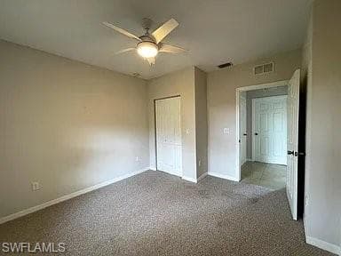 Unfurnished bedroom featuring visible vents, ceiling fan, baseboards, carpet flooring, and a closet