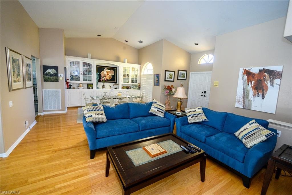 The living/dining combo space features lofted ceiling, and light wood-style floors, sliders out to the lanai.