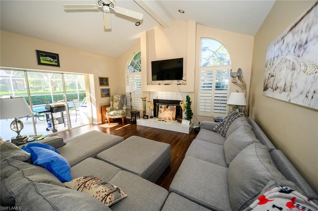 Living room with a wealth of natural light, a fireplace, lofted ceiling with beams, and wood finished floors