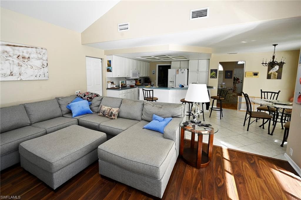 Living room featuring lofted ceiling, and wood finished floors and is open to the kitchen.