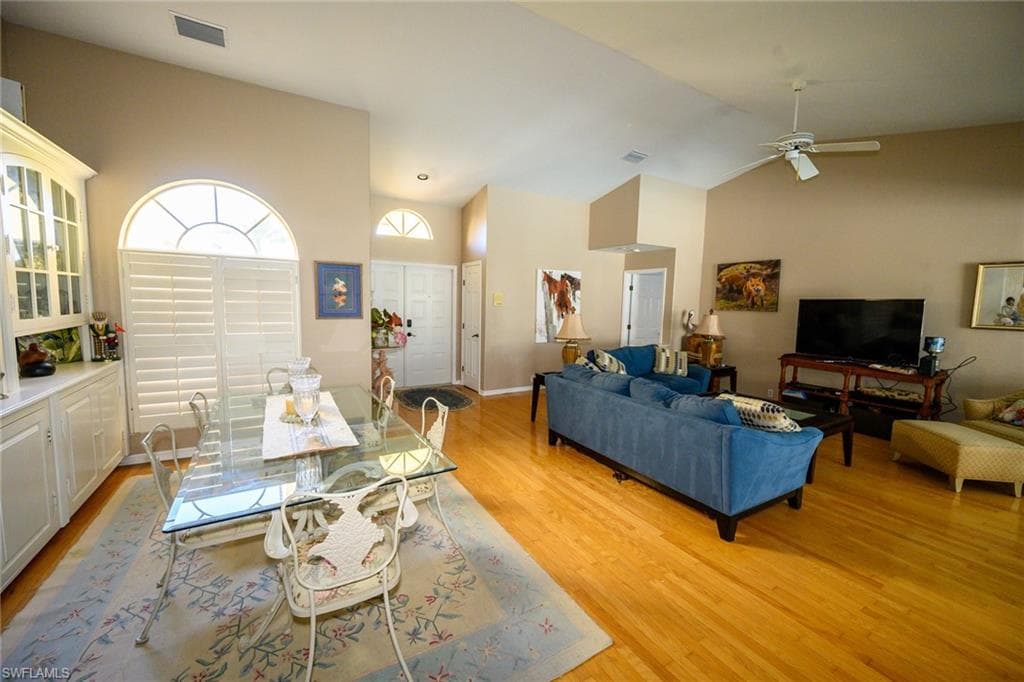 Dining room featuring high vaulted ceiling, light wood-style floors, and a ceiling fan