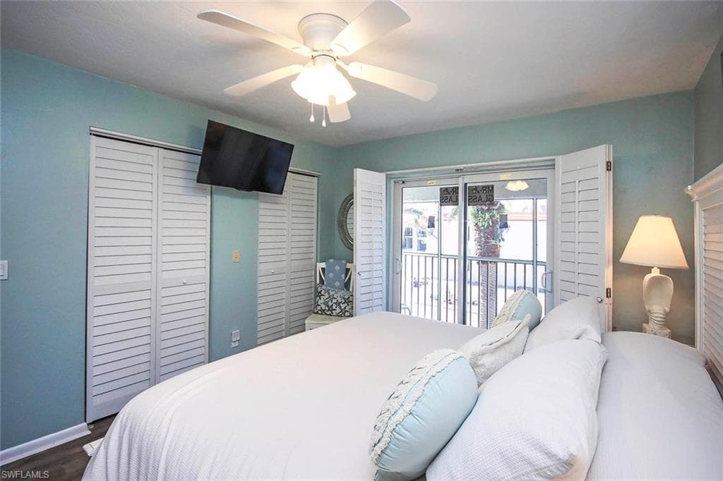 Bedroom featuring access to exterior, dark wood-style floors, baseboards, and ceiling fan