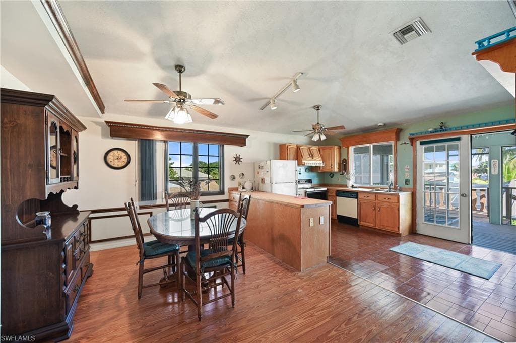 Dining space featuring dark wood finished floors, track lighting, and ceiling fan