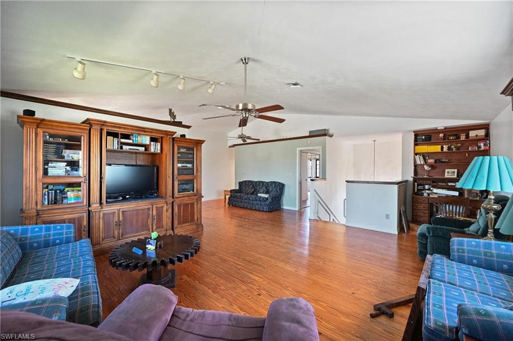 Living area with wood finished floors, a ceiling fan, lofted ceiling, and track lighting