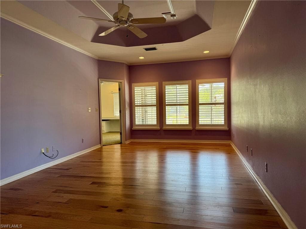 Spare room with crown molding, a raised ceiling, a ceiling fan, and hardwood / wood-style flooring