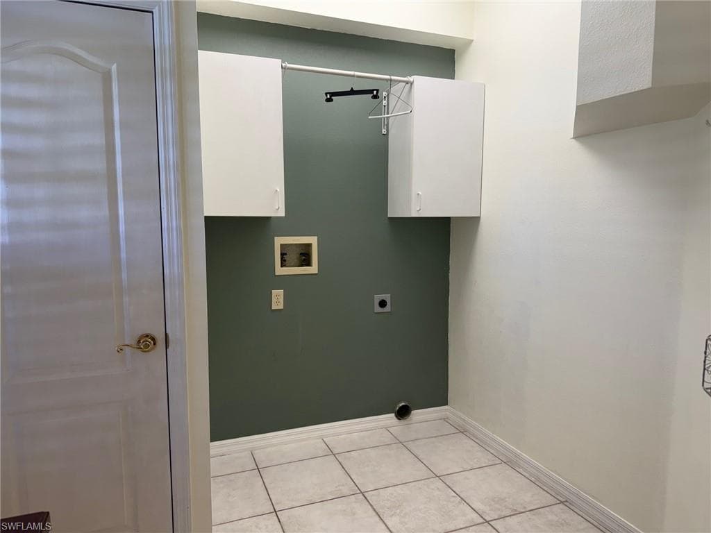 Washroom featuring baseboards, light tile patterned floors, hookup for a washing machine, cabinet space, and electric dryer hookup