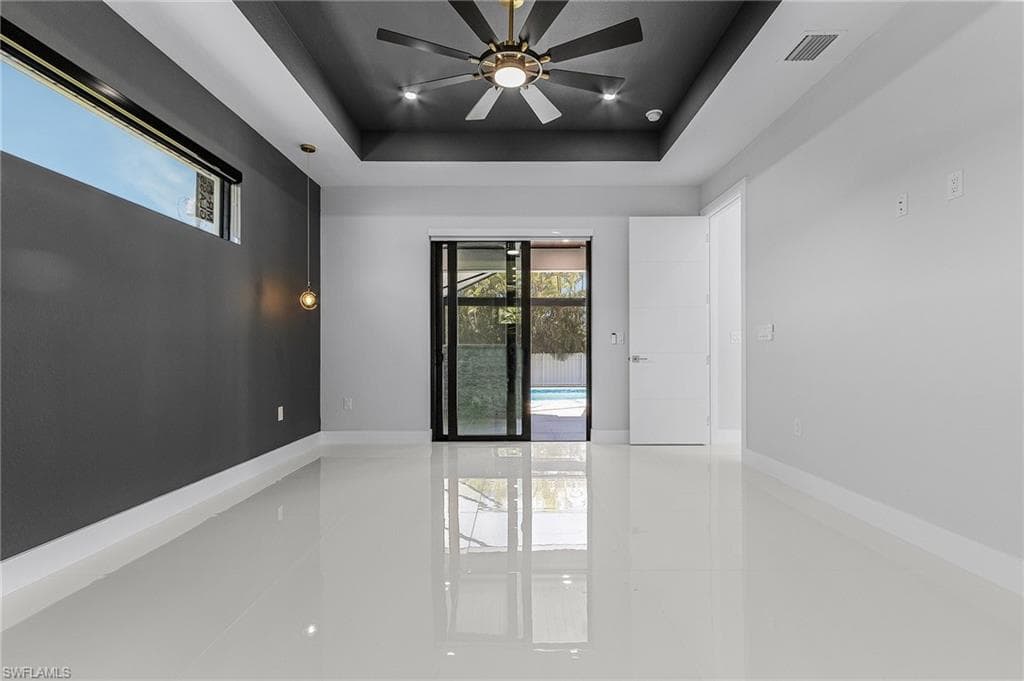 Spare room featuring visible vents, baseboards, a raised ceiling, and a ceiling fan