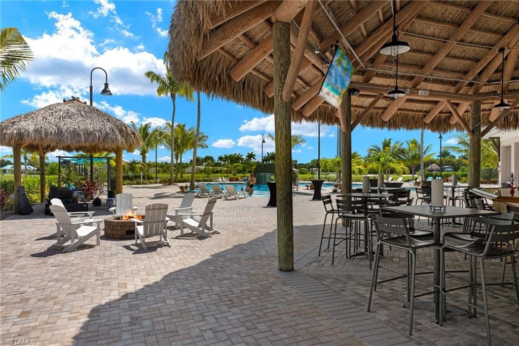 View of patio with a gazebo, a community pool, and an outdoor fire pit