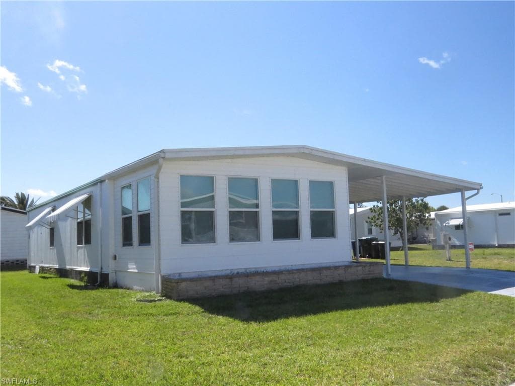 View of side of home featuring a lawn, driveway, and an attached carport