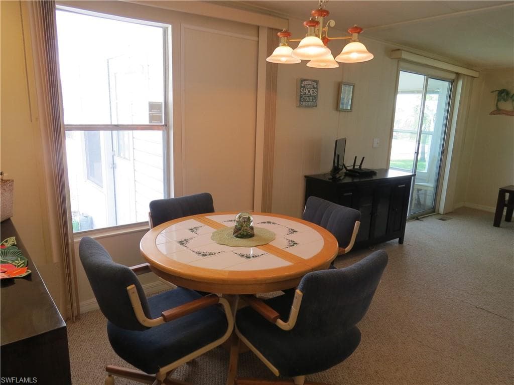 Carpeted dining area with a chandelier and baseboards
