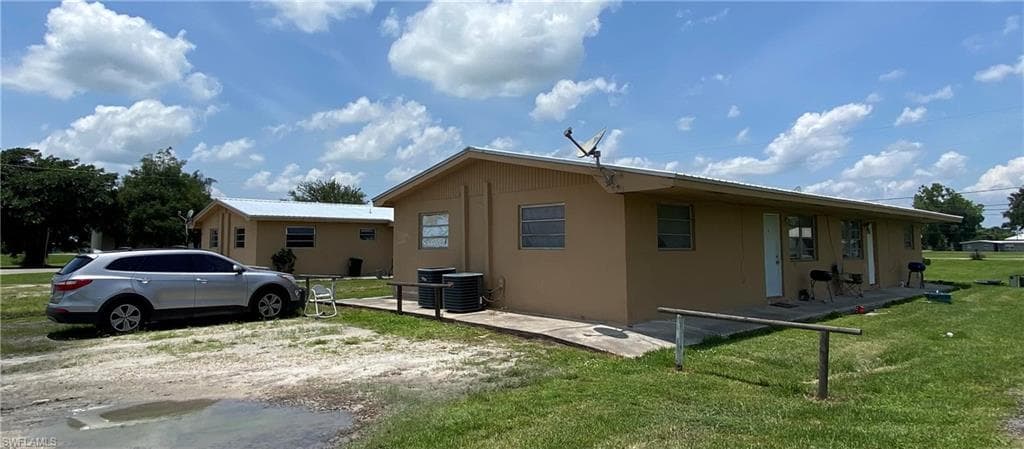 View of home's exterior with central AC, stucco siding, and a yard
