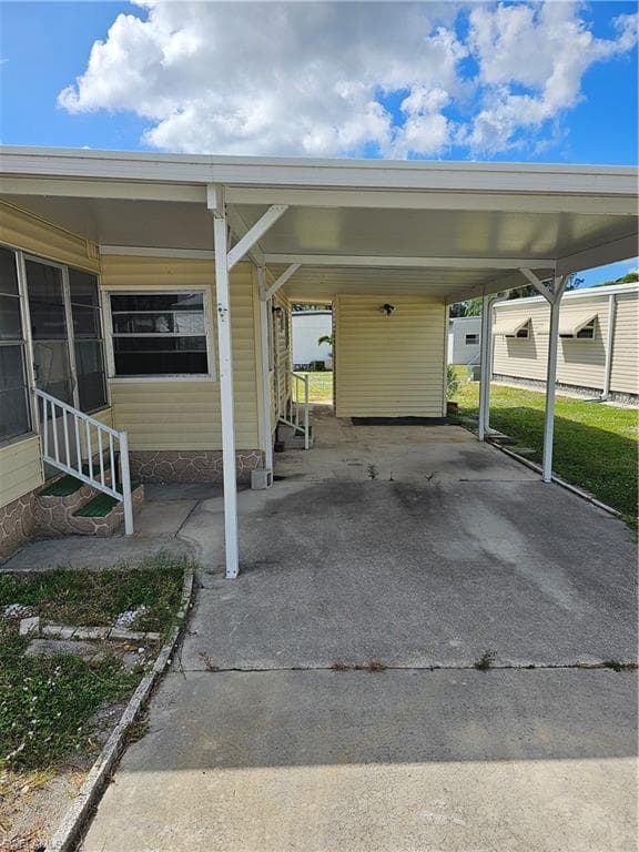 View of parking / parking lot with an attached carport, driveway, and entry steps