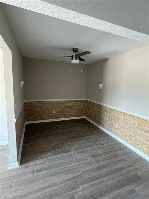 Unfurnished room with a wainscoted wall, wood finished floors, and ceiling fan