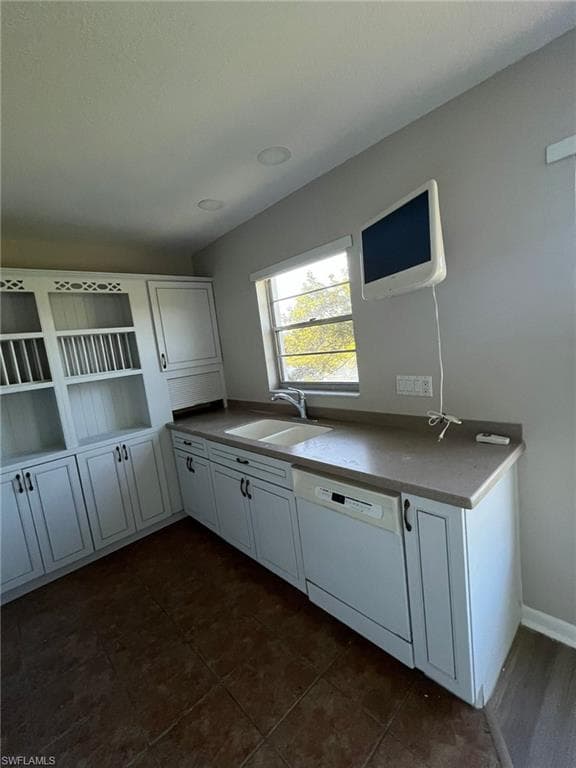Kitchen with white dishwasher, open shelves, a sink, and white cabinets