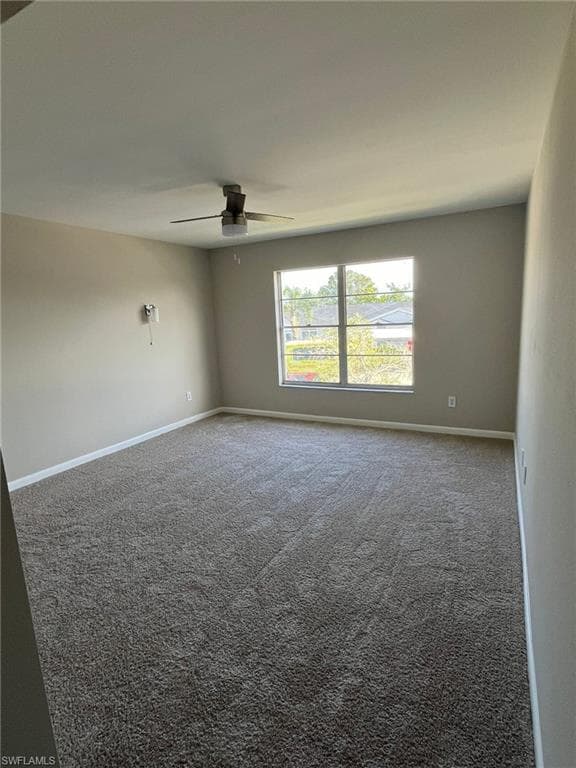 Empty room with carpet flooring, a ceiling fan, and baseboards