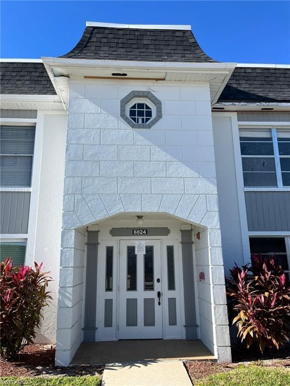 View of exterior entry featuring roof with shingles