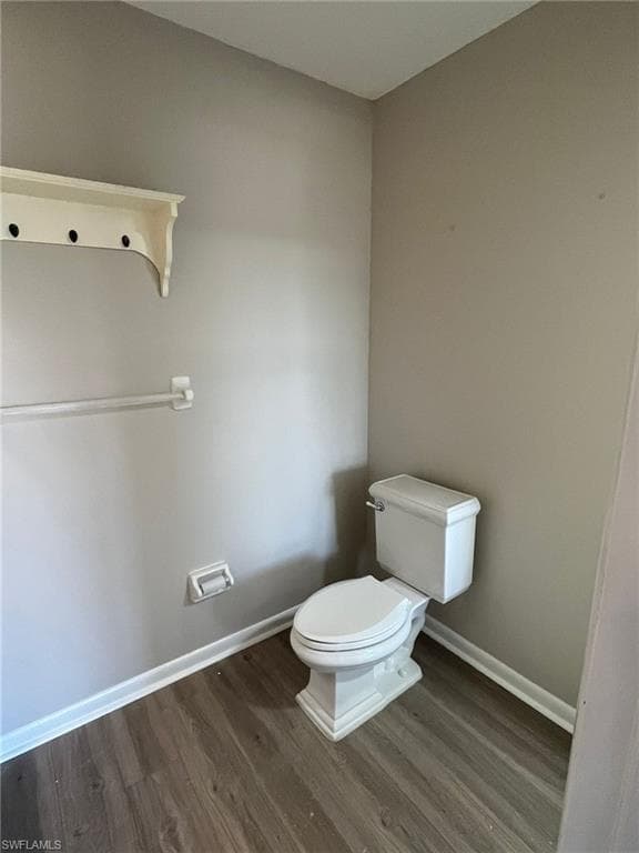 Bathroom featuring toilet, baseboards, and wood finished floors