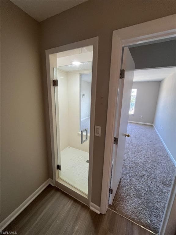 Hall with dark wood-type flooring, baseboards, and dark colored carpet