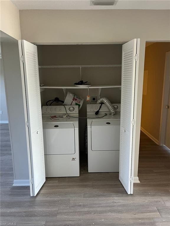 Laundry area featuring visible vents, baseboards, wood finished floors, laundry area, and washing machine and dryer