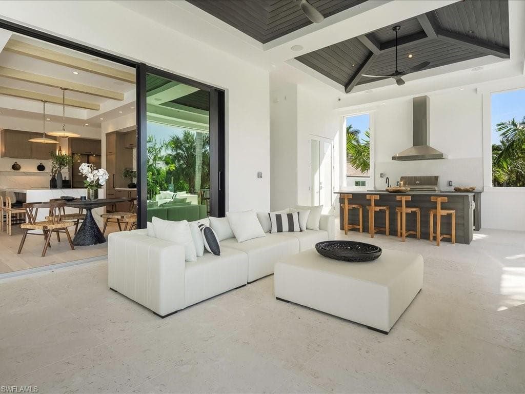 Living room with a high ceiling, beam ceiling, ceiling fan, and recessed lighting