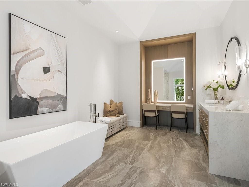 Full bathroom with marble finish floor, a freestanding bath, vanity, and lofted ceiling