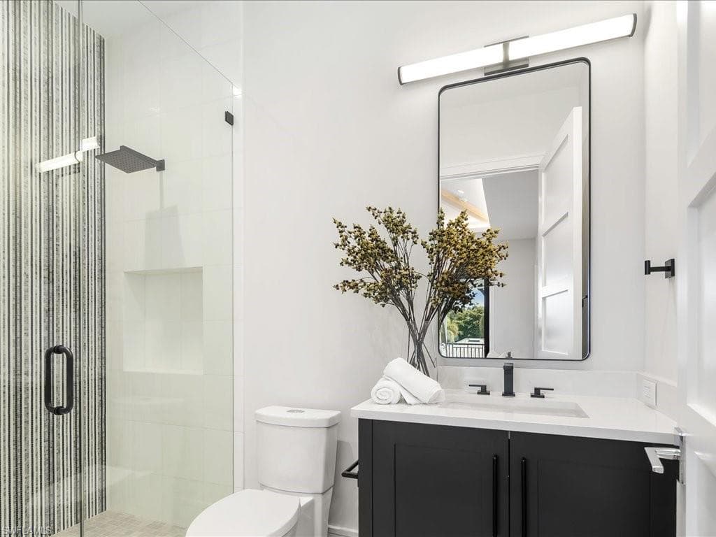 Full bathroom featuring toilet, a stall shower, and vanity