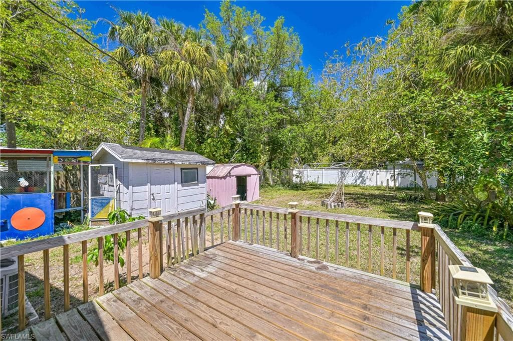 Deck with a lawn, a storage shed, fence, and an outbuilding