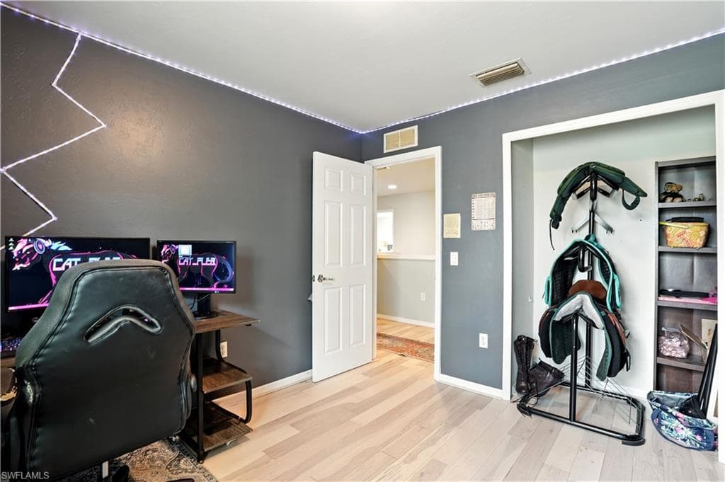 Versatile bedroom or home office with sleek dark gray walls, wood-look flooring, and a large window bringing in natural light. Ample space for desks, shelving, or creative setups makes it perfect for work-from-home, gaming, or hobbies. LED accent lighting adds a modern touch, while the neutral palette allows for easy personalization.