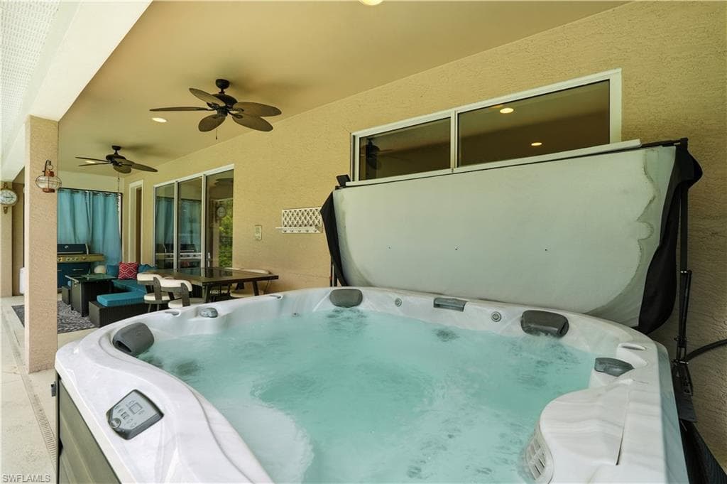 Inviting covered patio with a relaxing hot tub, perfect for unwinding after a day in the Florida sun. Ceiling fans provide comfort, while the spacious layout offers room for outdoor dining and lounging. Surrounded by lush preserve views and connected to the screened pool area, this outdoor retreat is ideal for entertaining or quiet evenings