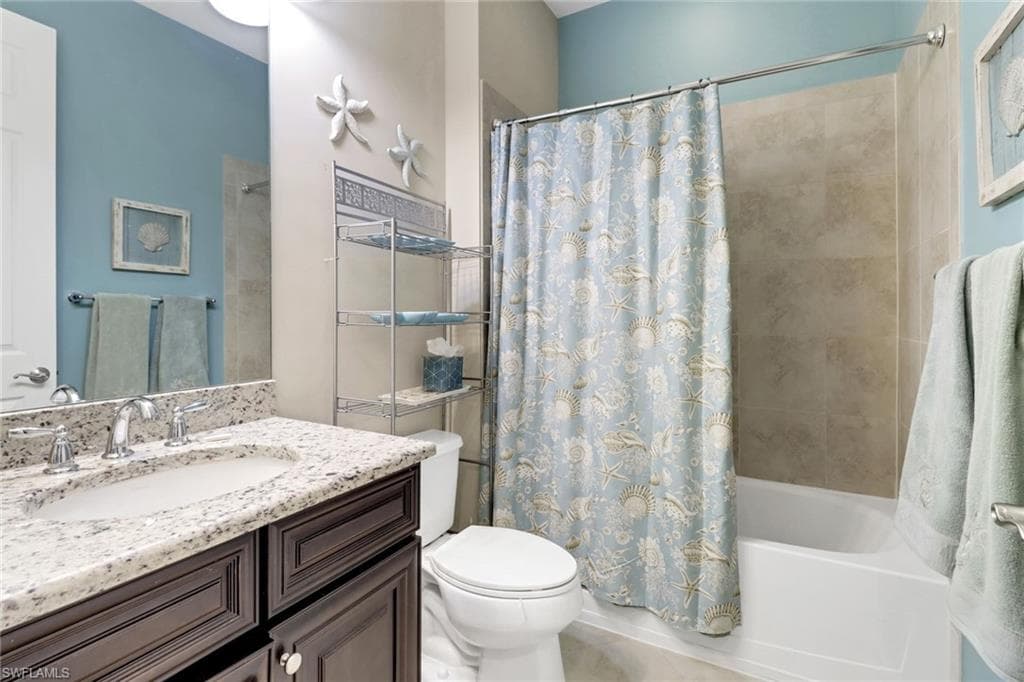 Full bathroom featuring toilet, vanity, and shower / bath combination with curtain