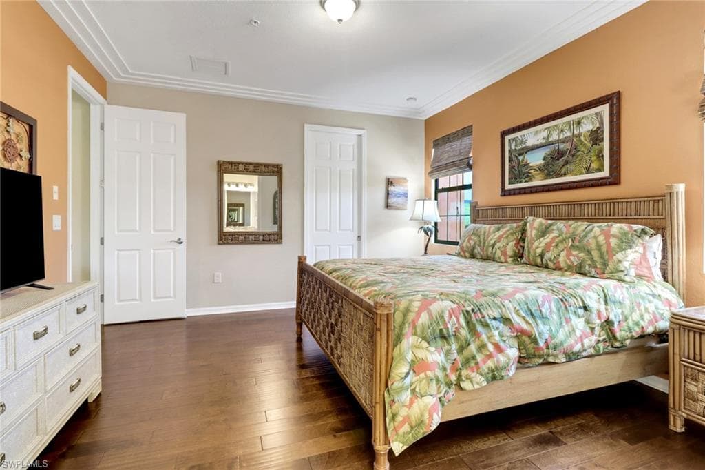 Bedroom featuring dark wood-style floors, baseboards, and ornamental molding