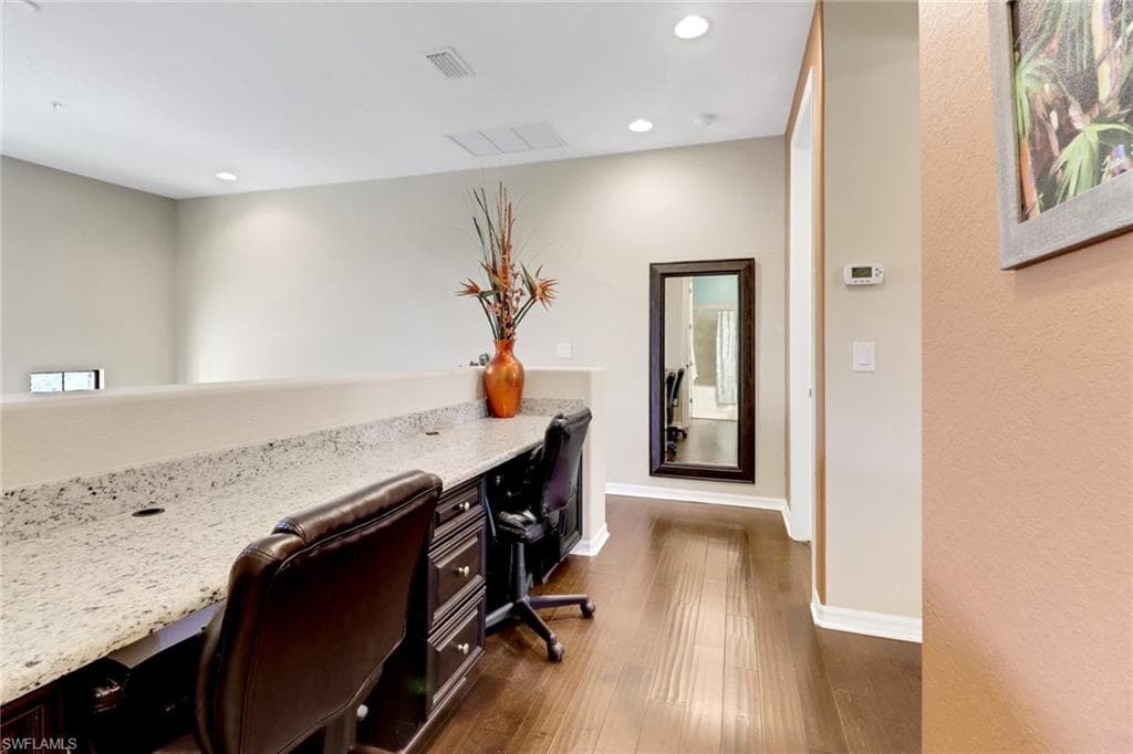 Home office featuring dark wood-style flooring, built in desk, baseboards, recessed lighting, and visible vents