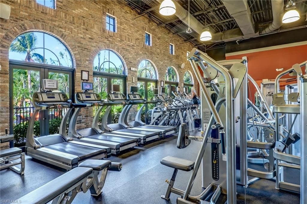 Gym featuring brick wall, a wealth of natural light, and a towering ceiling