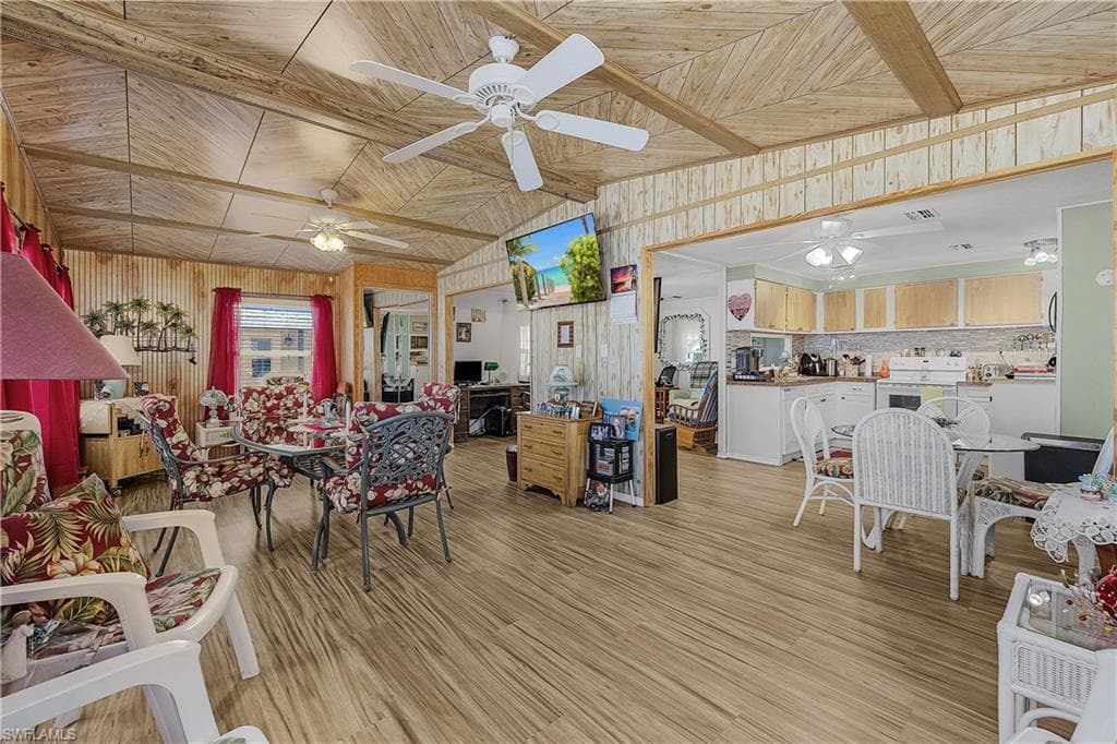 Living area with light wood-type flooring, wood walls, ceiling fan, and wood ceiling