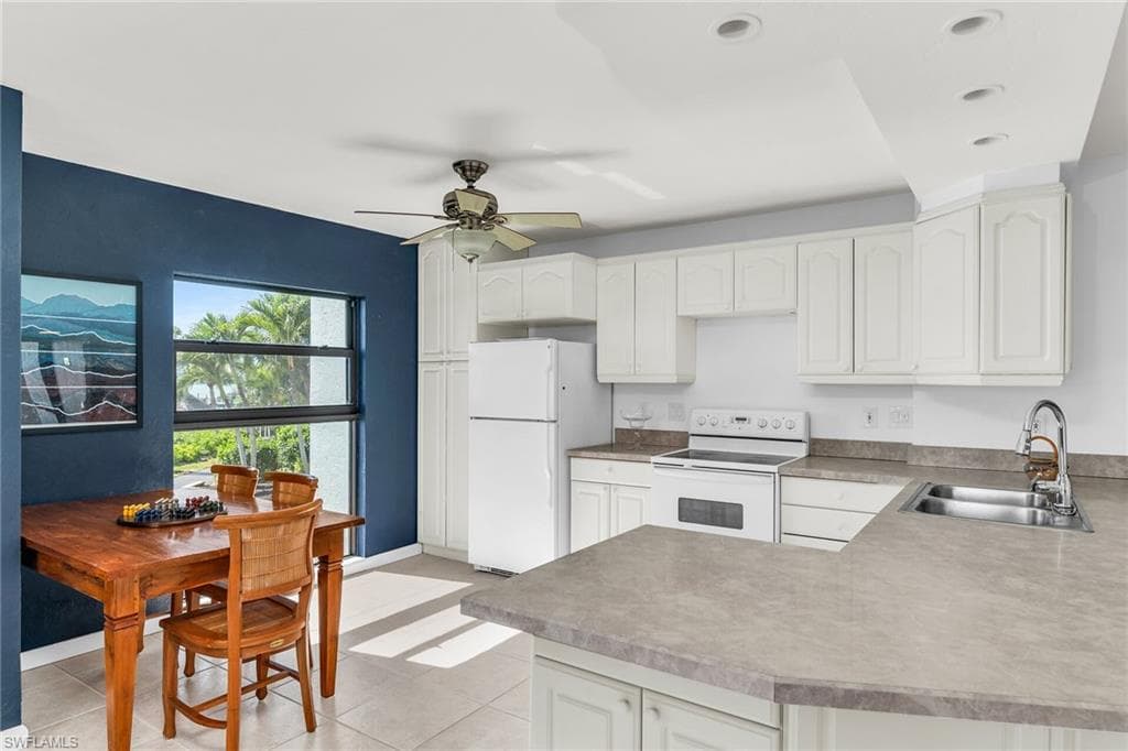 Kitchen featuring a sink, white cabinetry, white appliances, and light tile patterned flooring
