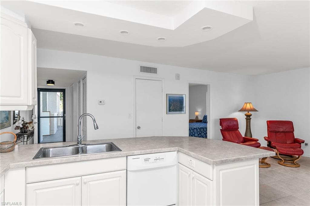 Kitchen with visible vents, dishwasher, a sink, light countertops, and white cabinetry