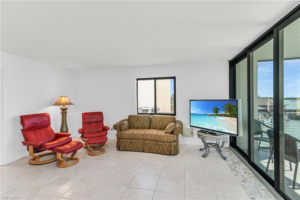 Living room featuring light tile patterned floors, baseboards, and floor to ceiling windows