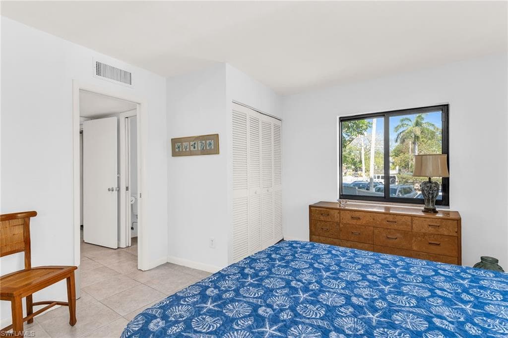 Bedroom featuring light tile patterned floors, visible vents, a closet, and baseboards