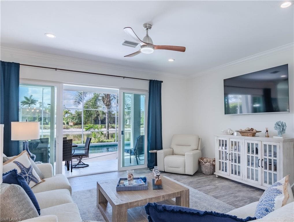 Living area with crown molding, a ceiling fan and recessed lighting