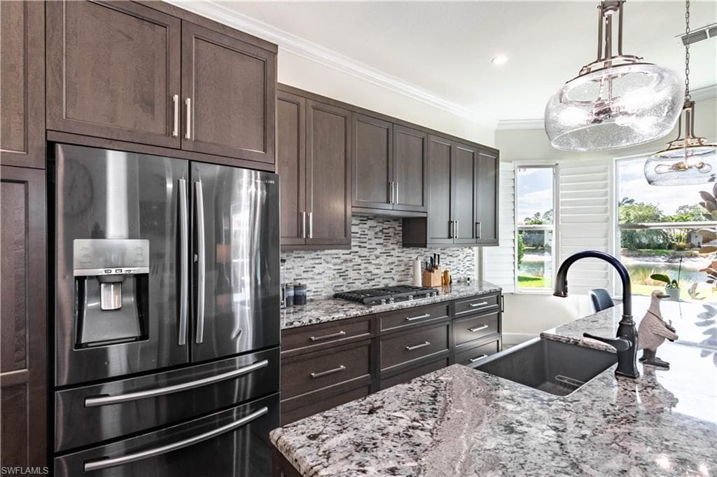 Kitchen featuring stainless steel appliances, a sink, dark brown cabinetry, and decorative backsplash