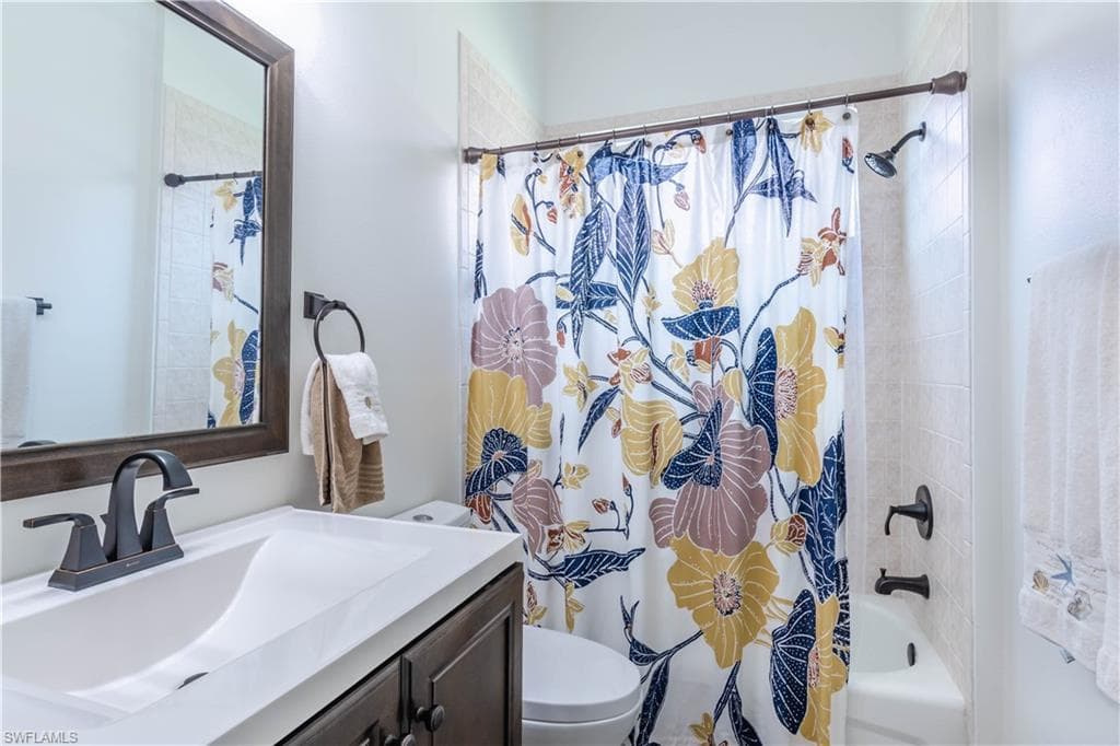 Full bath with toilet, vanity, and shower / bathtub combination with curtain