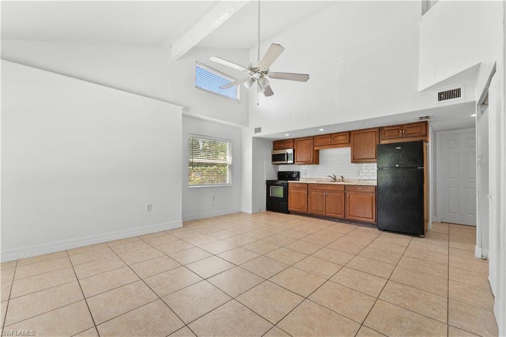 Kitchen with high vaulted ceiling, a ceiling fan, visible vents, black appliances, and light countertops