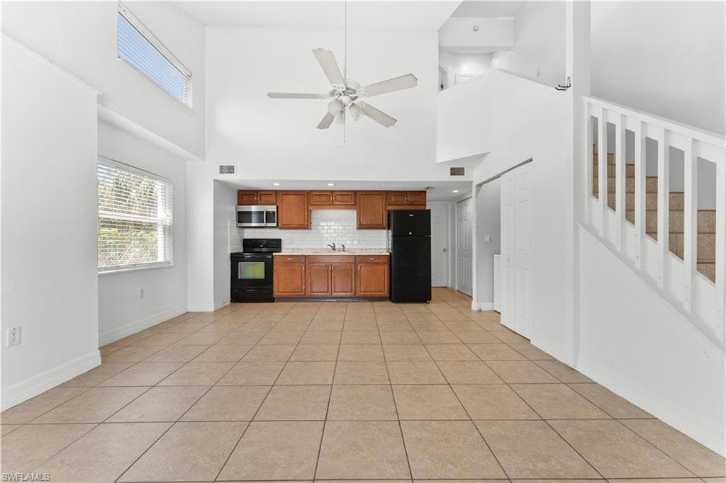 Kitchen featuring light countertops, black appliances, brown cabinets, decorative backsplash, and a sink