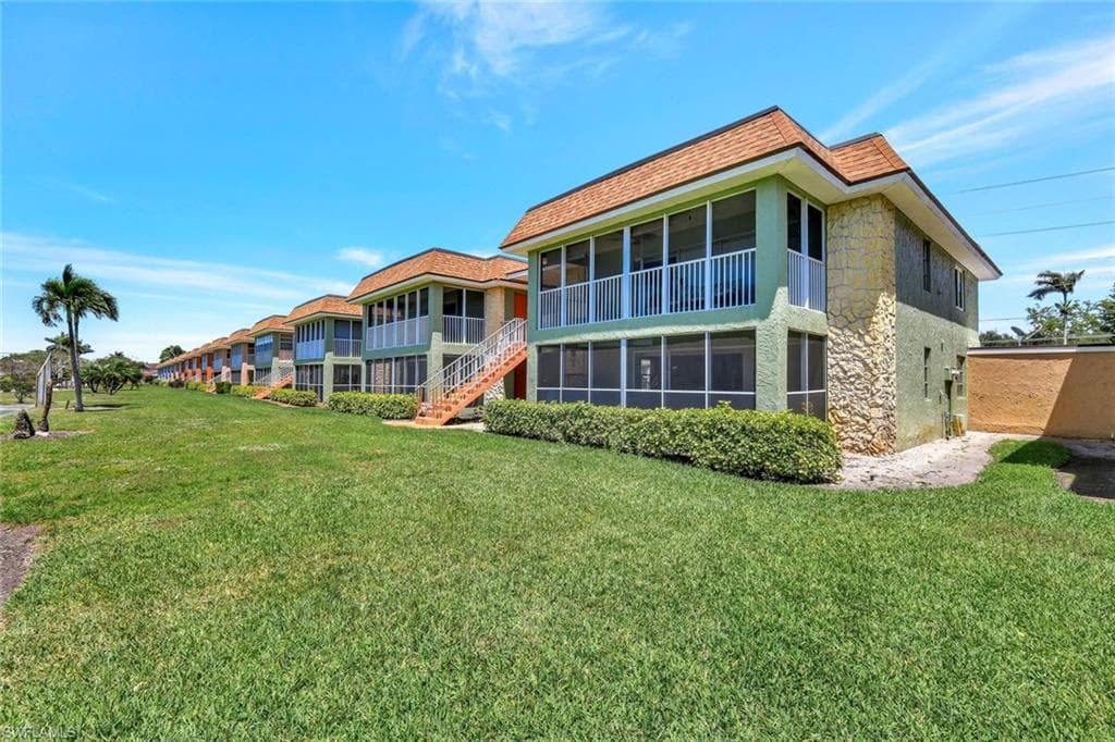 Back of property with a yard, a sunroom, and stone siding
