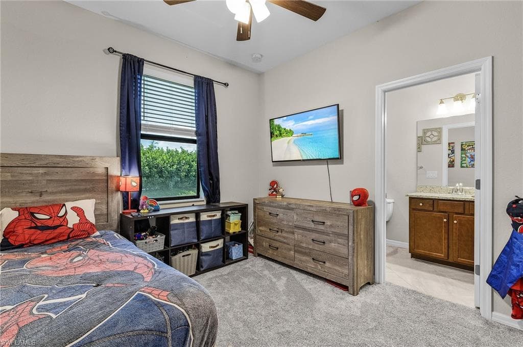 Bedroom with ensuite bath, a ceiling fan, and light carpet