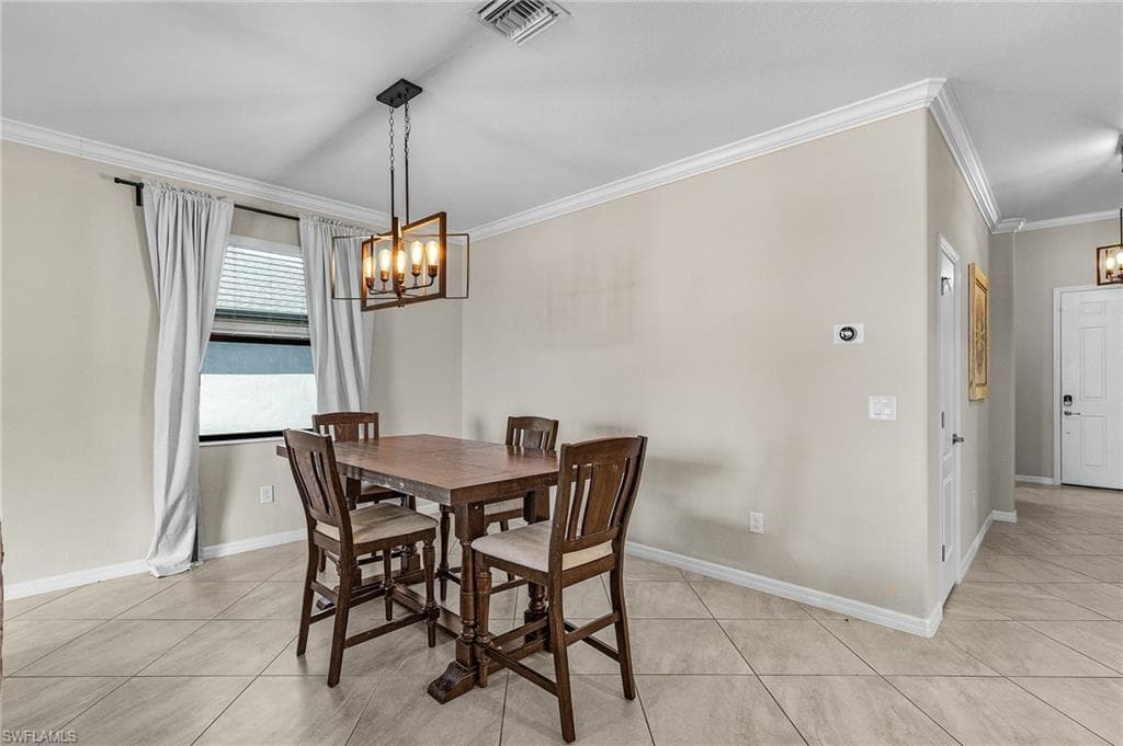 Dining area with crown molding, light tile patterned floors, an inviting chandelier, baseboards, and visible vents